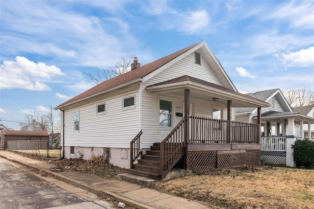 view of front facade featuring a porch, a chimney, and fence