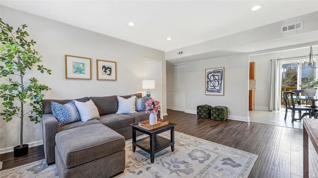 living room with visible vents, a notable chandelier, and wood finished floors