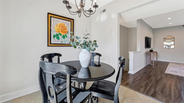 dining space with light tile patterned floors, baseboards, visible vents, and a notable chandelier