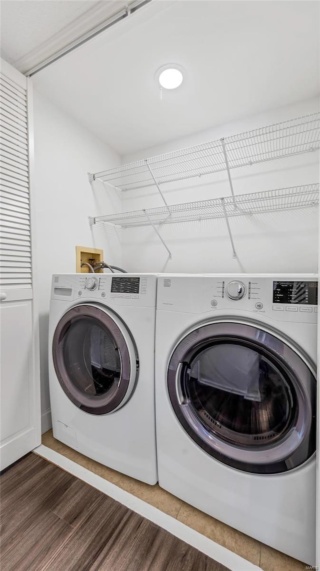 washroom with laundry area, wood finished floors, and washing machine and dryer