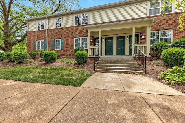 view of front of home with brick siding and a porch