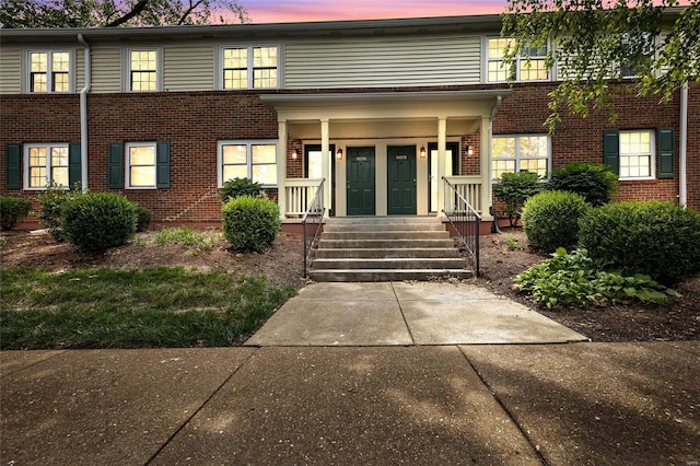 view of front of home with covered porch and brick siding