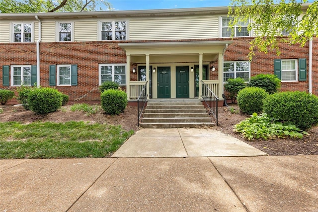 multi unit property with a porch and brick siding