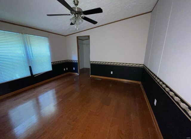 spare room featuring a textured ceiling, ornamental molding, vaulted ceiling, and wood finished floors