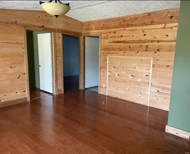 interior space with lofted ceiling, wood walls, and wood finished floors