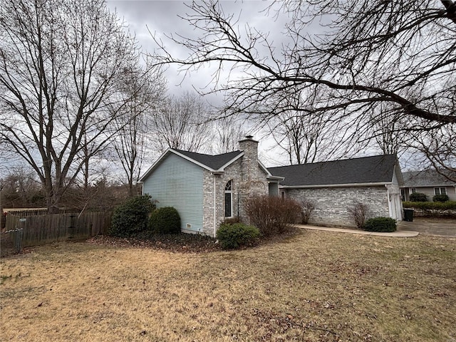 view of property exterior with a garage, a chimney, fence, and a lawn