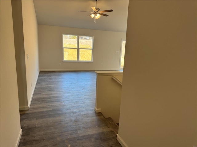 interior space featuring ceiling fan, dark wood-style flooring, and baseboards