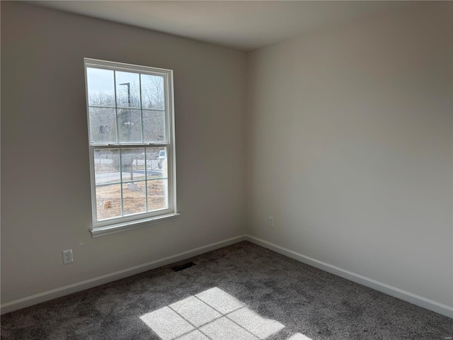 carpeted spare room with a wealth of natural light, visible vents, and baseboards