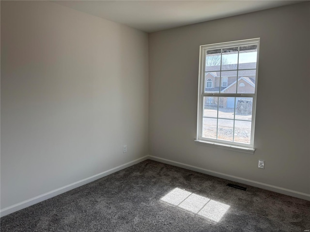 carpeted spare room featuring visible vents, baseboards, and a wealth of natural light