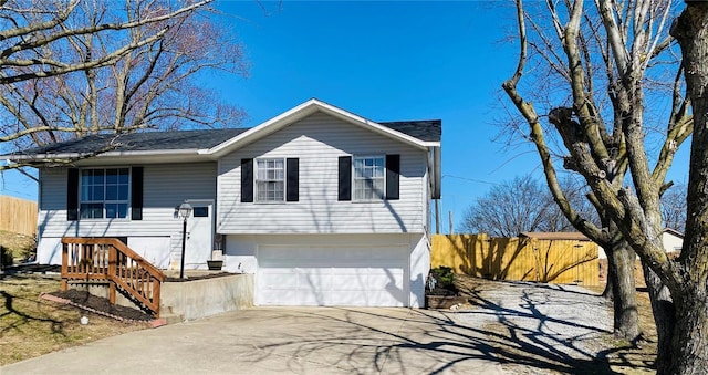 bi-level home with a garage, driveway, and fence