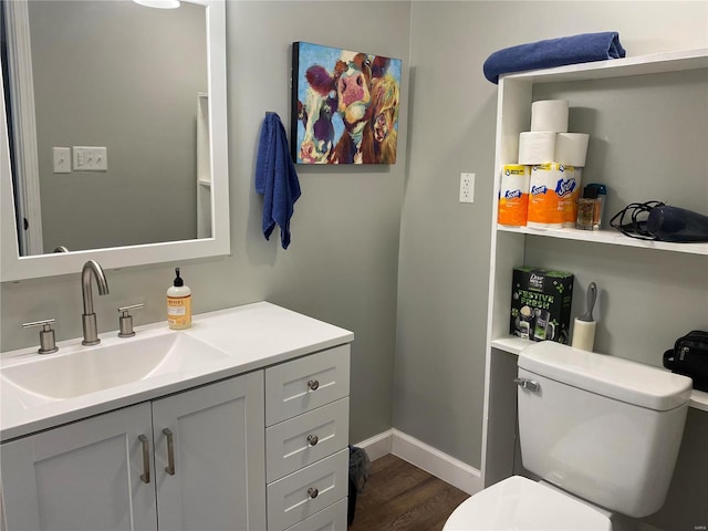 half bath with baseboards, toilet, wood finished floors, and vanity