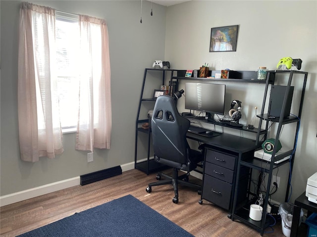 office featuring baseboards, a healthy amount of sunlight, and wood finished floors