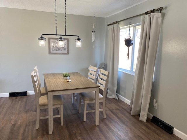 dining area with dark wood finished floors, visible vents, and baseboards