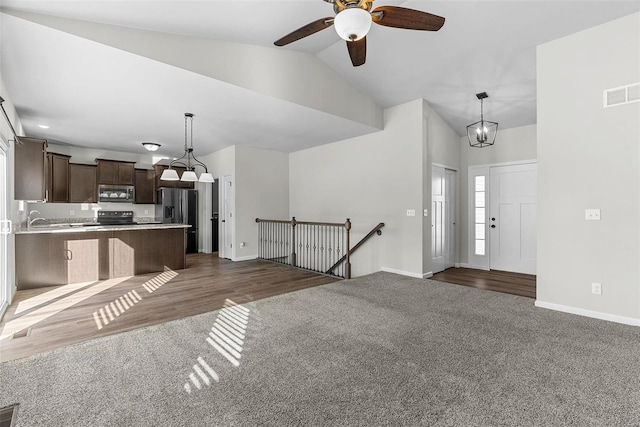 interior space featuring baseboards, visible vents, lofted ceiling, a sink, and ceiling fan with notable chandelier