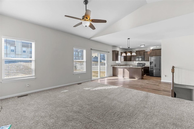 unfurnished living room featuring visible vents, baseboards, lofted ceiling, ceiling fan, and carpet