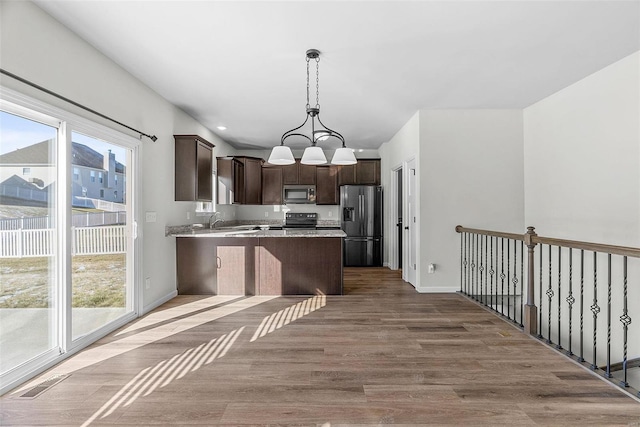 kitchen featuring dark brown cabinetry, appliances with stainless steel finishes, dark wood finished floors, and a wealth of natural light