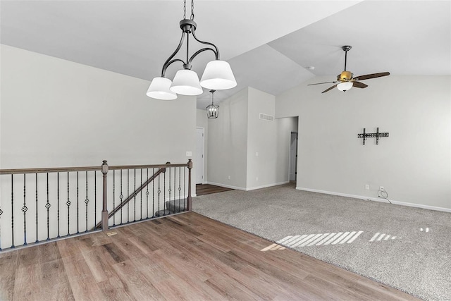 unfurnished room with lofted ceiling, ceiling fan, wood finished floors, visible vents, and baseboards