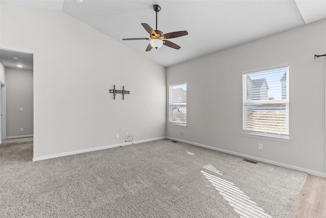 carpeted spare room with lofted ceiling, a wealth of natural light, and baseboards