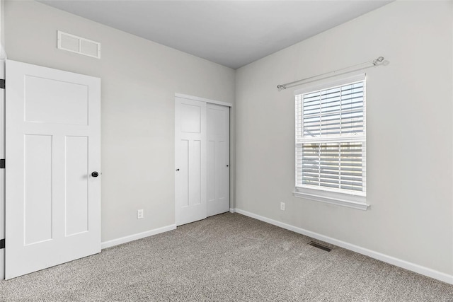 unfurnished bedroom with a closet, carpet, visible vents, and baseboards