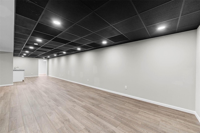 finished basement with recessed lighting, baseboards, a drop ceiling, and light wood finished floors