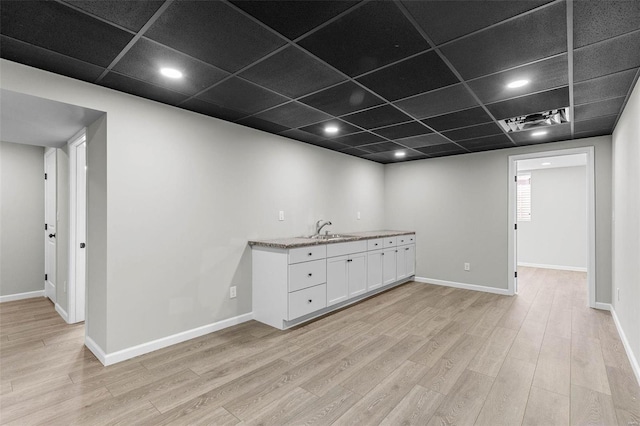 interior space with visible vents, a sink, light wood-style flooring, and baseboards