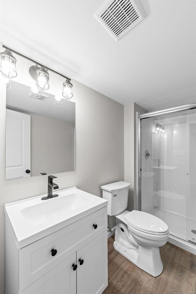 bathroom with toilet, a stall shower, wood finished floors, and visible vents