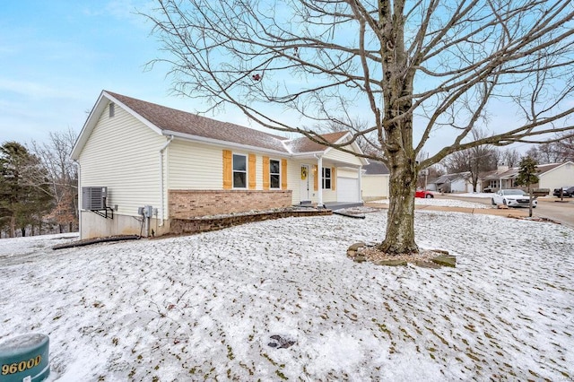 ranch-style house featuring cooling unit, brick siding, and an attached garage