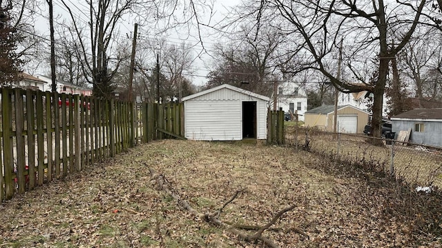 view of yard with a garage, a fenced backyard, and an outdoor structure