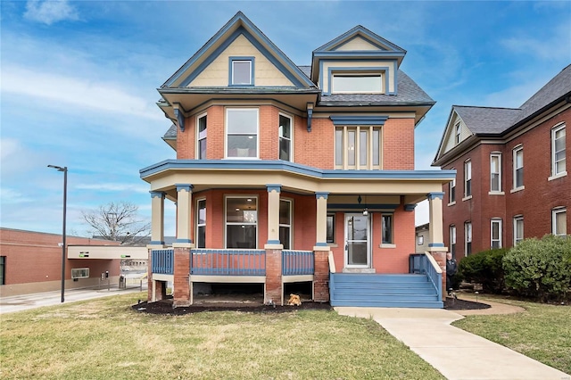 view of front facade featuring a porch, brick siding, a front lawn, and roof with shingles