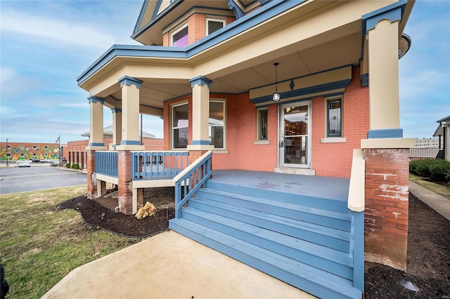 property entrance featuring a porch and brick siding