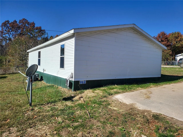 view of side of home with fence and a yard