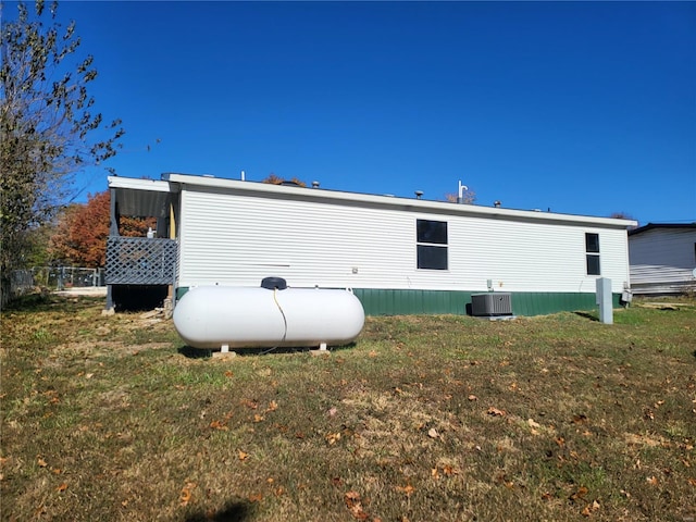 rear view of property featuring a lawn, fence, and central air condition unit