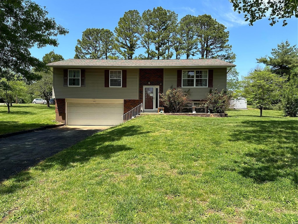 split foyer home featuring a front lawn, brick siding, driveway, and an attached garage