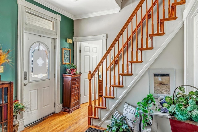 foyer entrance with ornamental molding, stairs, and wood finished floors