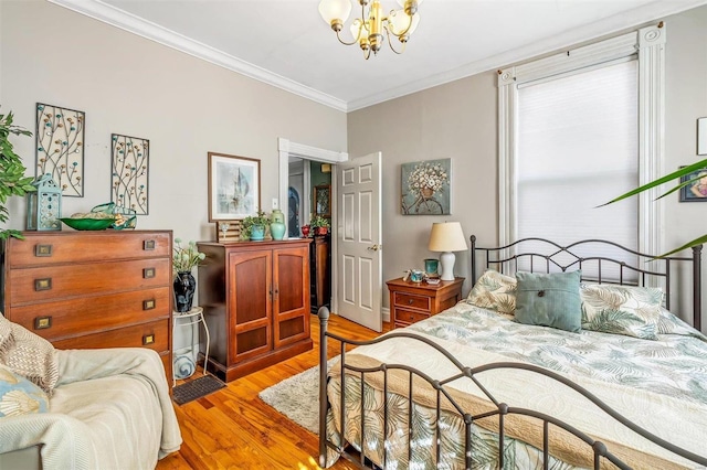 bedroom featuring light wood-style flooring, ornamental molding, and a notable chandelier