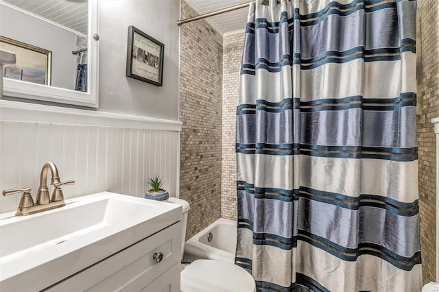 bathroom featuring wainscoting, shower / bathtub combination with curtain, toilet, and vanity