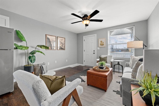 living room featuring ceiling fan, baseboards, and wood finished floors