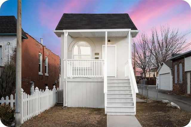 view of front of home with stairway, fence, covered porch, and roof with shingles