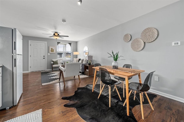 dining room with ceiling fan, baseboards, and dark wood-style flooring