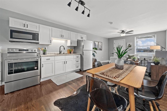 kitchen with a sink, stainless steel appliances, dark wood-type flooring, light countertops, and white cabinetry