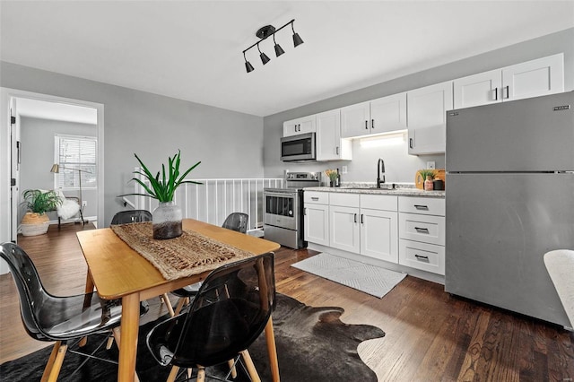 kitchen with a sink, dark wood-type flooring, white cabinetry, and stainless steel appliances