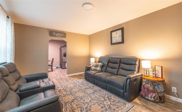 living area with arched walkways, baseboards, and wood finished floors