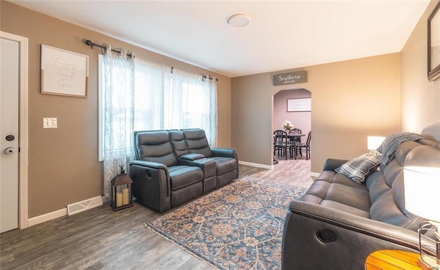 living room with baseboards, visible vents, arched walkways, and wood finished floors