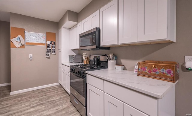 kitchen with white cabinets, stainless steel microwave, baseboards, and gas range oven