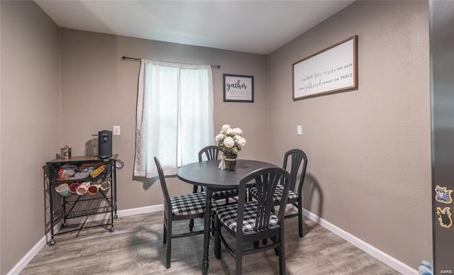 dining area with baseboards and wood finished floors