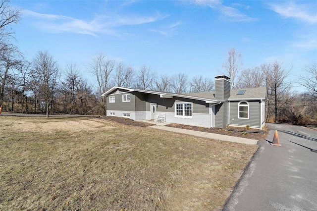 single story home featuring a front yard, driveway, and a chimney