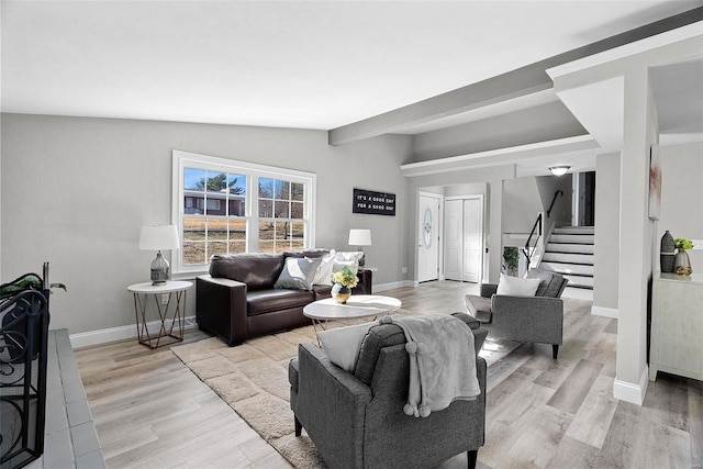 living area featuring light wood-type flooring, stairs, baseboards, and vaulted ceiling