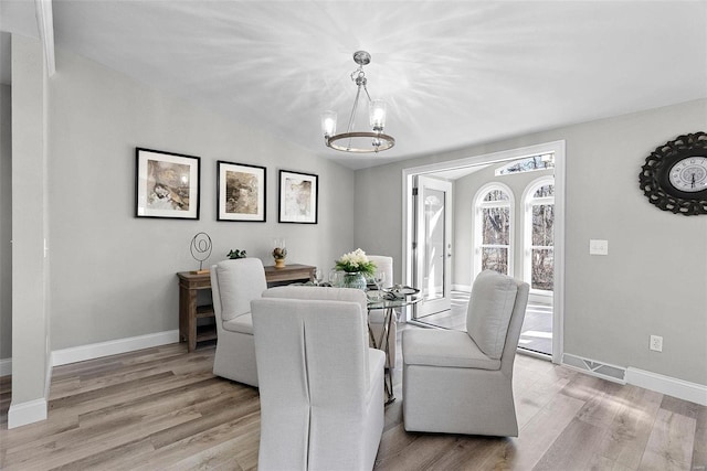 dining room featuring a chandelier, vaulted ceiling, baseboards, and light wood-style floors