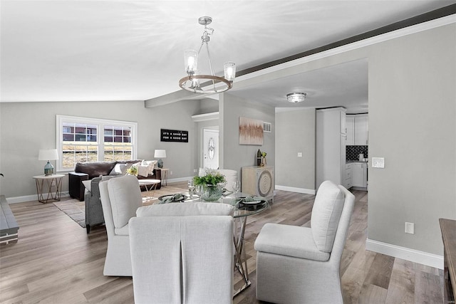 dining space featuring lofted ceiling, light wood-style floors, and a notable chandelier