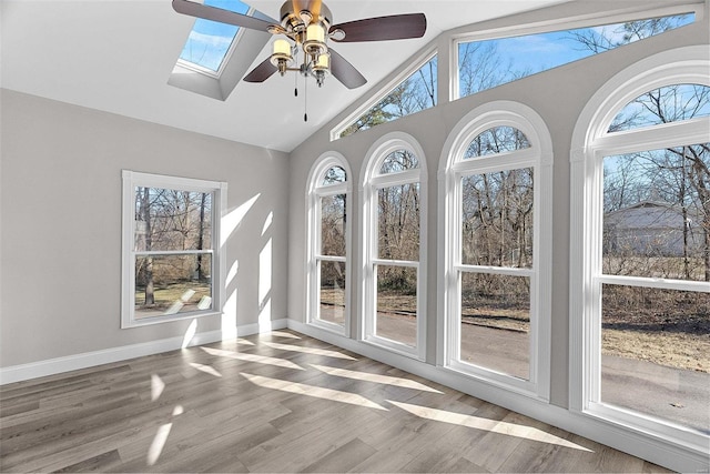 unfurnished sunroom with ceiling fan and lofted ceiling with skylight